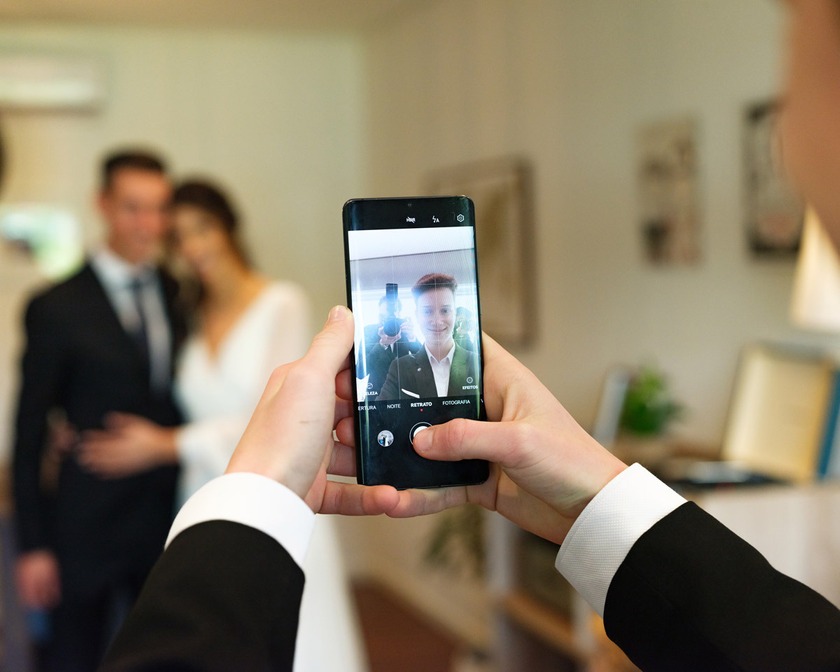 Noiva e convidados em casamento, captura espontânea de momento íntimo com telemóvel, emoção e alegria