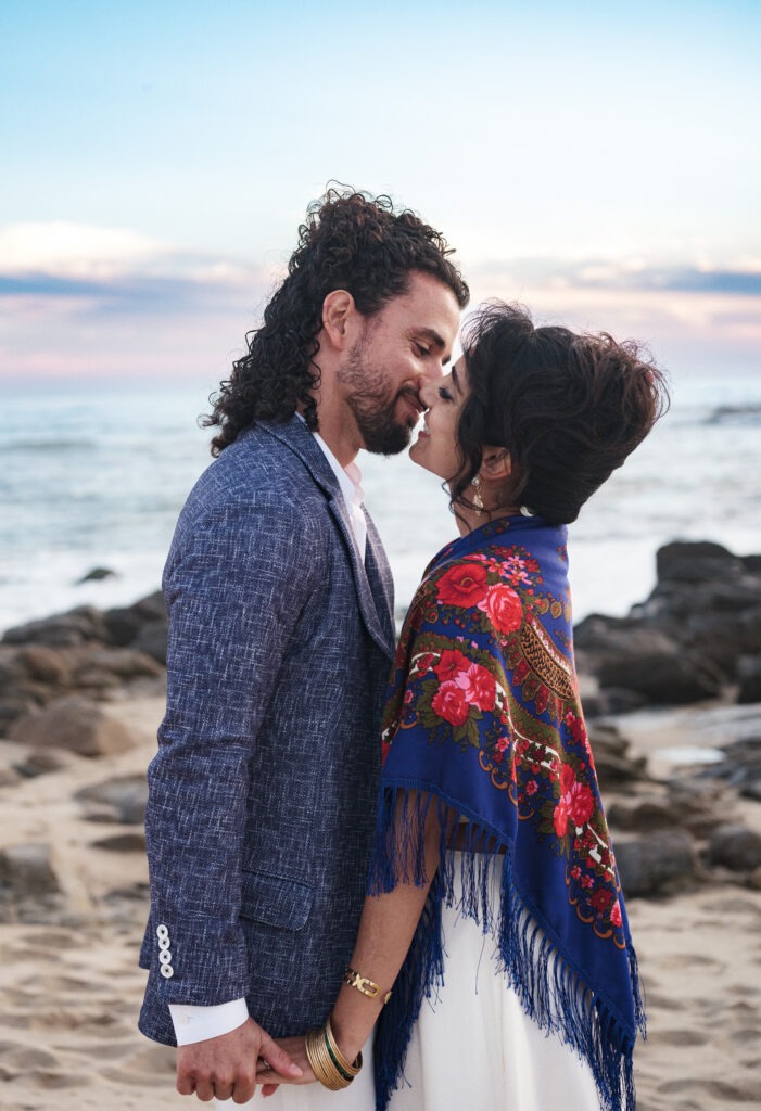 Noivos na sessão de pré-casamento na praia, estando centrados na imagem prestes a beijarem -se. 