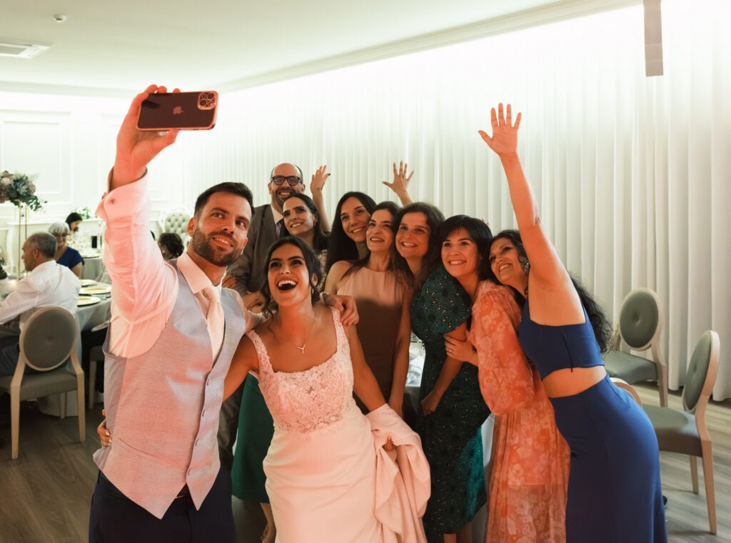 Noivos divertidos com alguns convidados enquanto tiram um selfie todos juntos. 