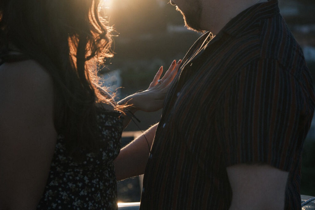 Pedido de casamento ao pôr do sol, close-up dos noivos observando o anel de noivado que esta colocado na mão esquerda da noiva. 