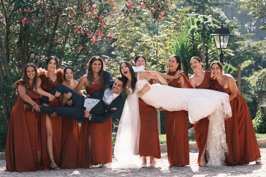 Momento divertido entre noivos e madrinhas, estando elas a pegar nos noivos