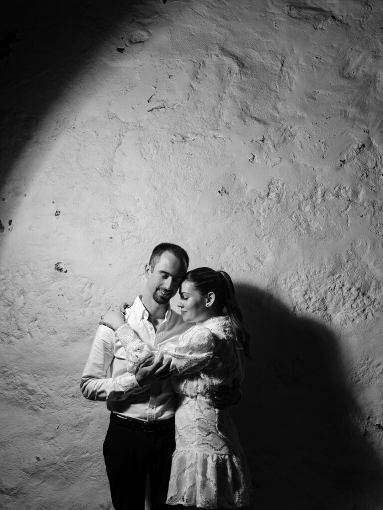 Noivos em abraço íntimo em parede rústica, fotografia romântica de casamento por Filipe Santos Porto