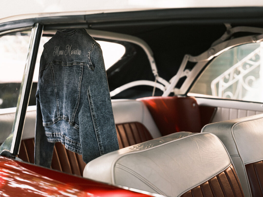 Casaco de ganga pendurado no interior do carro clássico vermelho, onde a noiva vai ser levada para a cerimónia. 