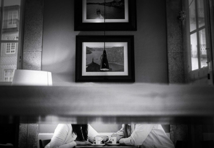 Casais relaxados em sofá sob luz quente, intimidade e tranquilidade em ambiente acolhedor com fotografias decorativas