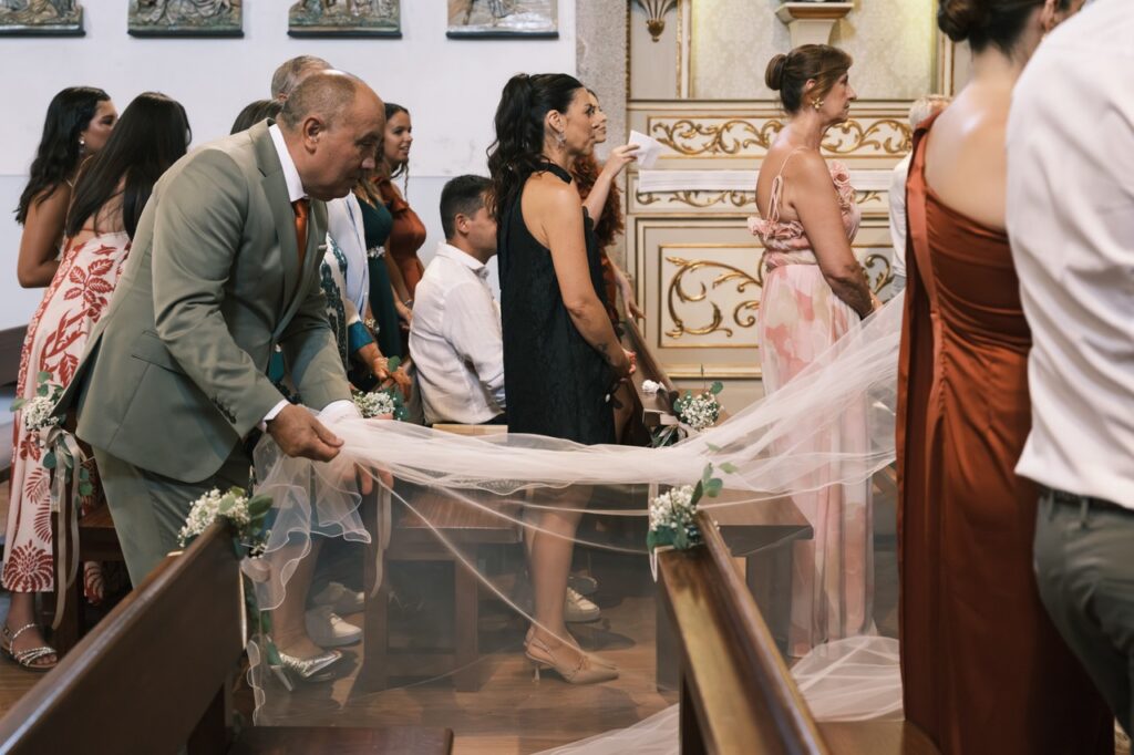 Pai da noiva a compor o véu da noiva durante a cerimónia de casamento