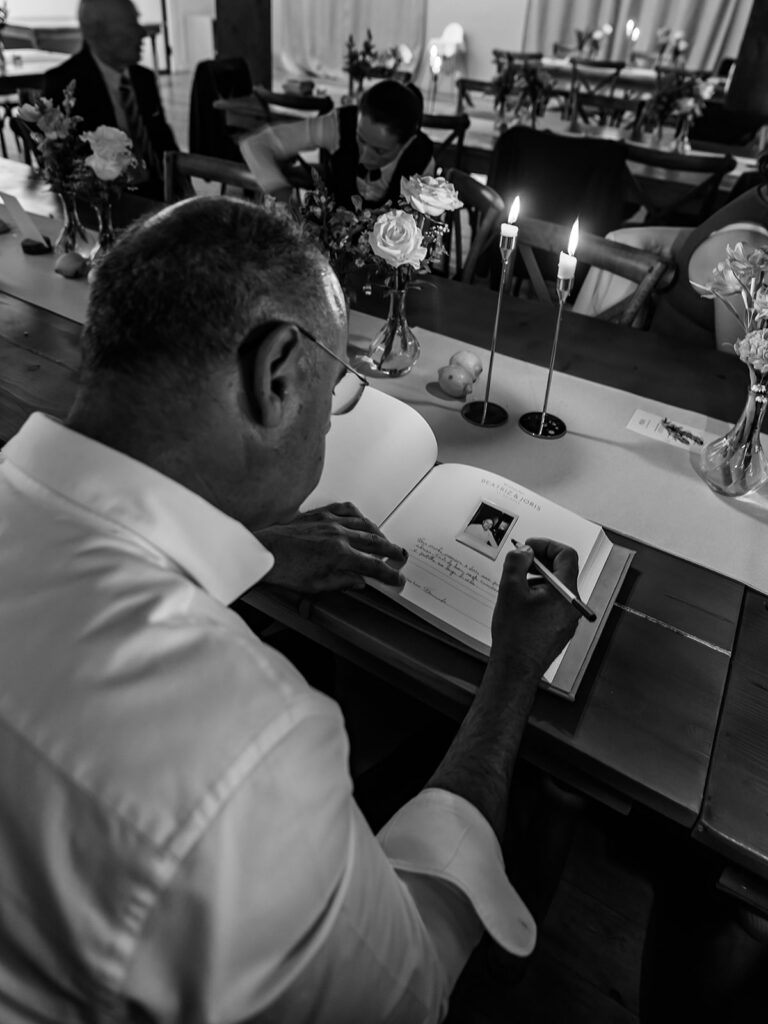 Senhor a escrever num livro de recordação para os noivos, imagem a preto e branco