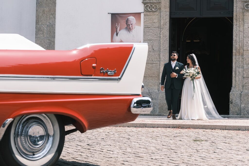 Pequena sessão com os noivos à saída da igreja com o carro clássico em primeiro plano. 
