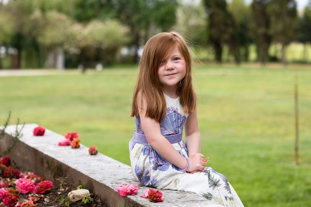 Menina com um estido florido a sorrir para a câmara docemente. 