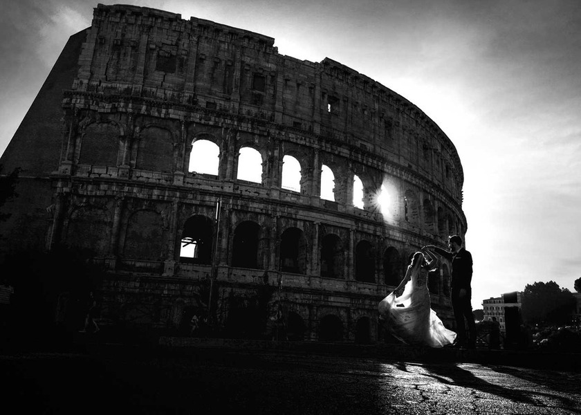 Noivo e noiva em pose romântica à frente do Coliseu, luz dramática e elegância em casamento histórico