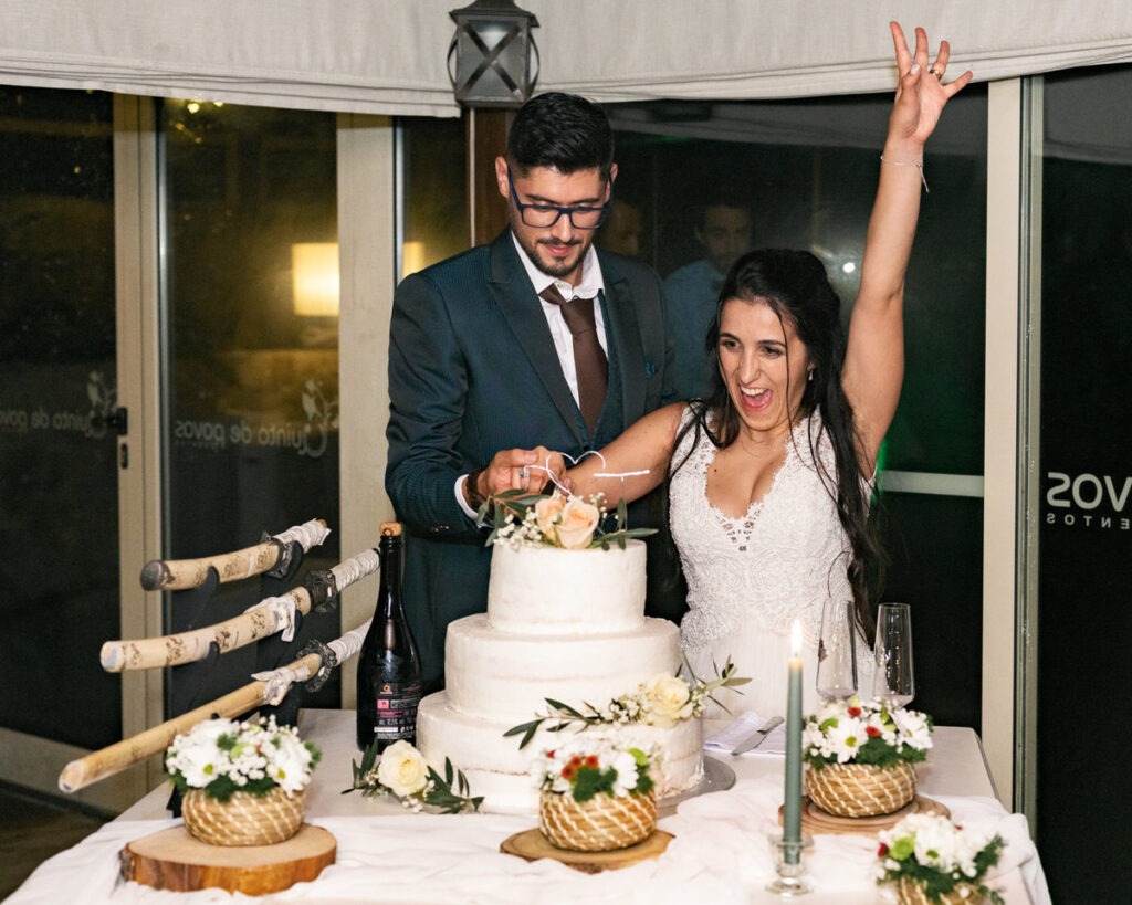 Noivos a cortar o bolo de três andares, noiva celebra com braço erguido na Quinta de Govos, registo documental animado.